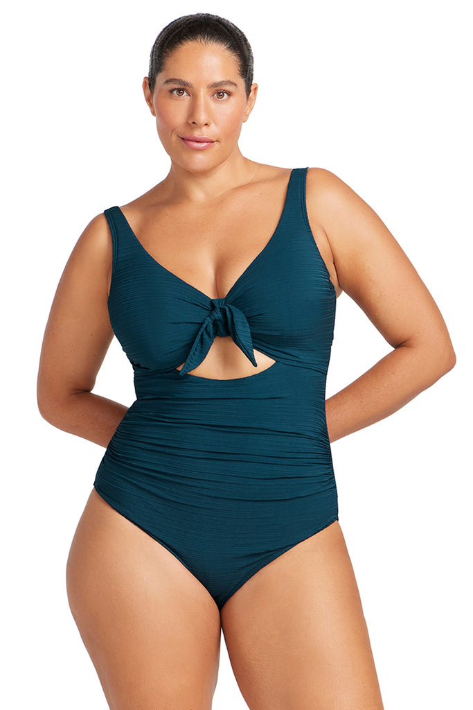 Woman wearing a navy swimsuit with a cutout design on a white background